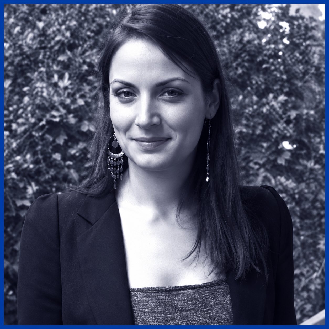 Portrait de Camille de Kermel, en noir et blanc teinté de bleu, sur un fond de feuillage.